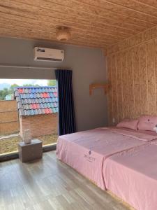 1 dormitorio con cama rosa y ventana en Việt Kiều Royal, en Xuyên Mộc