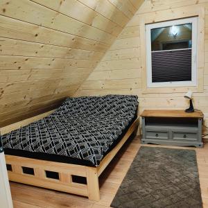 Una cama en una habitación de madera con ventana. en beskid.house1, en Spytkowice