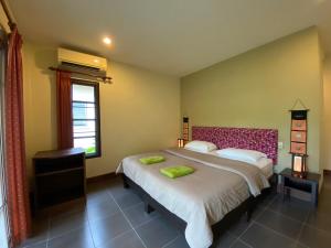 a bedroom with a large bed and a window at Sweet Mango Khaolak in Khao Lak