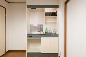 a kitchen with white cabinets and a sink in a room at Lavie Heights in Osaka