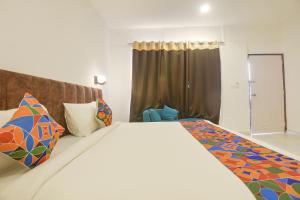 1 dormitorio con 1 cama grande y almohadas coloridas en FabHotel Morjim Bliss, en Morjim