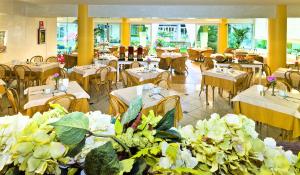 a restaurant with white tables and chairs and tables and flowers at Hotel Montecarlo in Bibione