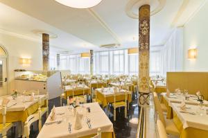 a restaurant with white tables and yellow chairs at Hotel Montecarlo in Bibione