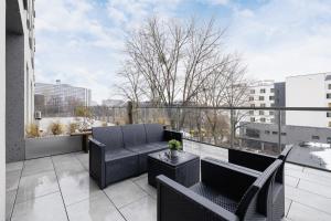 a balcony with black furniture and a view of a city at Exclusive Apartment in Katowice with Balcony, Parking, Gym and Sauna by Renters in Katowice