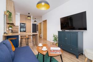 a living room with a blue couch and a kitchen at Exclusive Apartment in Katowice with Balcony, Parking, Gym and Sauna by Renters in Katowice