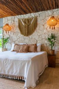a bedroom with a white bed with a stone wall at Luz de Luna Tulum Suite I in Tulum