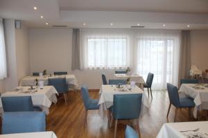 une salle à manger avec des tables blanches et des chaises bleues dans l'établissement Hotel Argentum by Bergkristall, à Fleres