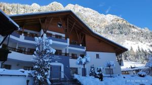 un bâtiment recouvert de neige avec une montagne en arrière-plan dans l'établissement Hotel Argentum by Bergkristall, à Fleres