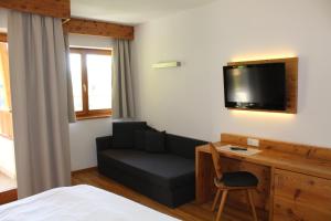 Cette chambre d'hôtel dispose d'un canapé et d'une télévision. dans l'établissement Hotel Argentum by Bergkristall, à Fleres