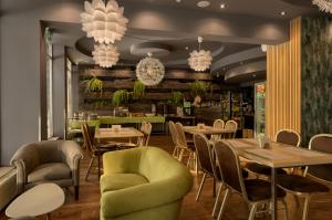 a restaurant with tables and chairs and chandeliers at Płonia Resort in Szczecin