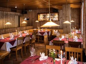 una sala da pranzo con tavoli, sedie e luci di Dorfgasthof Adler a Mellau