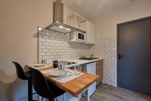 a small kitchen with a wooden table and chairs at Le Jayan - Charmant studio à Agen in Agen