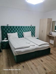 a bedroom with a large bed with a green headboard at LukAmi Green Home in Făgăraş