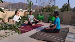three people sitting on the floor in a yoga pose at Vedic Life Homestay in Jaipur