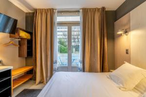 a bedroom with a bed and a large window at Hôtel Astoria in Nantes