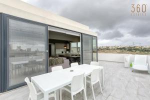 einen weißen Tisch und Stühle auf dem Balkon in der Unterkunft LUX Duplex Penthouse w/ Expansive Rooftop Terrace by 360 Estates in San Ġwann
