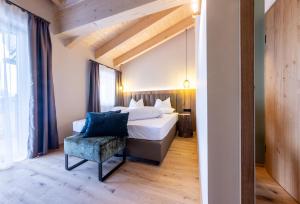 a bedroom with a bed and a blue chair at Höflehner Premium Gumpen Lodge in Haus im Ennstal