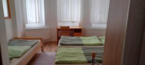 two beds in a room with a desk and windows at Penzión Sandrik in Hodruša