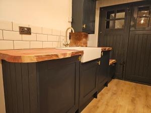uma cozinha com um lavatório e uma porta preta em The Little Mews em Blockley