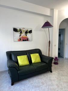 a black couch with two yellow pillows in a living room at Le case di Edo in Latina