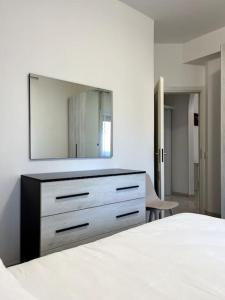 a white bedroom with a dresser and a mirror at Le case di Edo in Latina