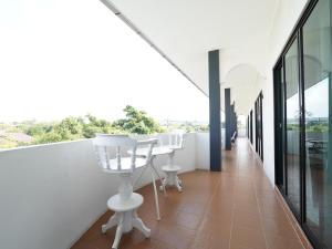 a balcony with white chairs and a table on it at RoomQuest One Bangsaray in Bang Sare