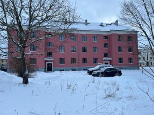 a red building with a car parked in a snow covered yard at Saunaga korter Tapa kesklinnas! in Tapa
