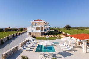 a resort with a pool and chairs and a building at Anna Mare Luxury Apartments in Afitos