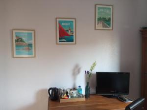a desk with a television and pictures on the wall at LA PETITE MEUNIERE in Tramain