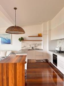 a kitchen with white cabinets and a wooden table at Shed. Holiday Apartment in Nelson Bay