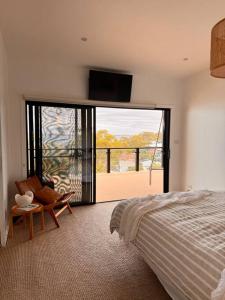 a bedroom with a bed and a large sliding glass door at Shed. Holiday Apartment in Nelson Bay