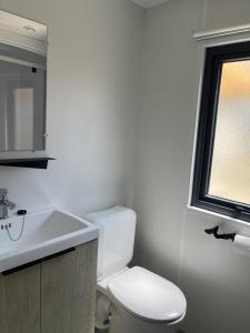 La salle de bains blanche est pourvue de toilettes et d'un lavabo. dans l'établissement LES DUNES - TORREILLES - Chez Cassandre et Nico, à Torreilles
