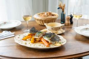 un plato de comida en una mesa de madera con copas de vino en Mercure Château de Fontainebleau, en Fontainebleau