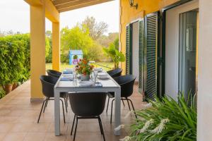 una mesa blanca con sillas negras en el patio en Son Serra country villa for 4 near Buger, en Búger