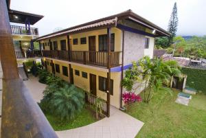 ein Haus mit einem Balkon und einem Hof mit Pflanzen in der Unterkunft Velas Chalés in Ubatuba