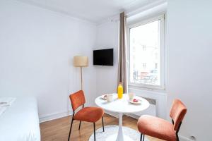 ein Wohnzimmer mit einem weißen Tisch und Stühlen in der Unterkunft Studio Avenue Philippe Auguste in Paris