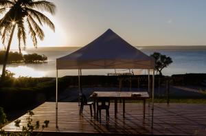 a table with a tent on a deck with the ocean at Canto das Amêijoas in Inhambane