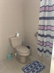 a bathroom with a toilet and a shower curtain at Blue Summer Suites in Bingag