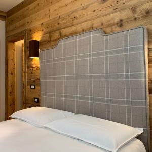a bed with a gray padded headboard with white pillows at Piccolo gioiello di montagna in Villanova