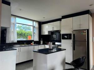 a kitchen with white cabinets and a large window at SBs Apartment in Suva