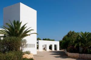 um edifício branco com uma palmeira em frente em Meditur Puglia by Itafirst Hotels em Specchiolla