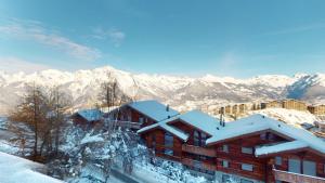a building covered in snow with mountains in the background at Pracondu 1 301 - OUTDOOR & FUN apartment 6 pers in Nendaz