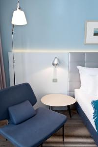a room with a couch, chair, lamp and a lamp post at Hotel AM MEER & Spa in Binz