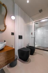 a bathroom with two black toilets and a sink at Tenuta Zamparina in Montignoso