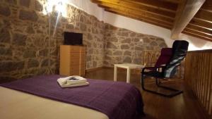 a bedroom with a bed and a chair and a tv at Quinta da Idalina in Monchique