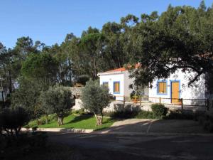 una pequeña casa blanca con puertas azules y árboles en Quinta da Idalina en Monchique