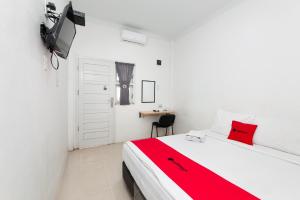 a bedroom with a bed with a red blanket at RedDoorz Syariah near RSUD Zainoel Abidin Banda Aceh in Banda Aceh
