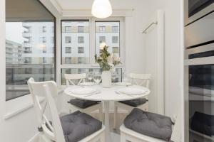 une salle à manger blanche avec une table et des chaises blanches dans l'établissement Business Apartment Mokotów by Noclegi Renters, à Varsovie