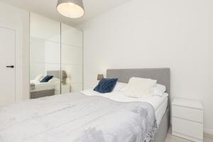 une chambre blanche avec un grand lit avec des oreillers bleus dans l'établissement Business Apartment Mokotów by Noclegi Renters, à Varsovie