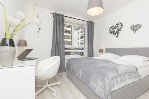 une chambre blanche avec un lit, un bureau et une fenêtre dans l'établissement Business Apartment Mokotów by Noclegi Renters, à Varsovie